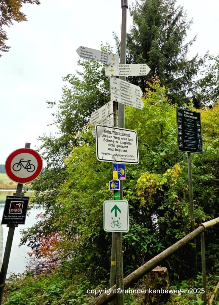 Foto van wegwijzer paal met veelheid (14) met aanduidingen  voor fietsers, wandelaars, zwemmers en lopers van Jacobspad voor het essay met welke bril kijk je naar de wereld.