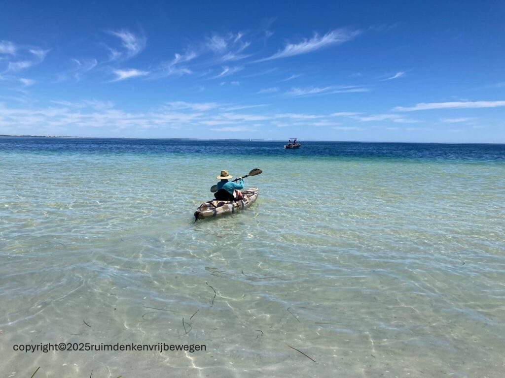 Een persoon in een kano op zee met de blik gericht op een vissersboot op een prachtige zonnige dag in Coulta, Zuid-Australië. Het verwijst naar een eigen koers varen in een wereld waar veel afleiding is en waarbij de actie van Dry January op aanhaakt. 